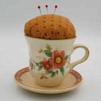 This is the front of the pincushion showing the flowers on the cup as well as the details on the trim of the saucer. This is the front of the pincushion showing the flowers on the cup as well as the details on the trim of the saucer.